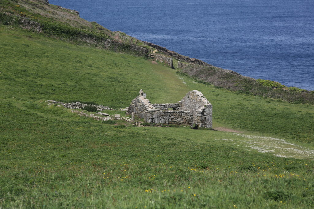 Ruined building in a field at Cape Cornwall with the sea in the background