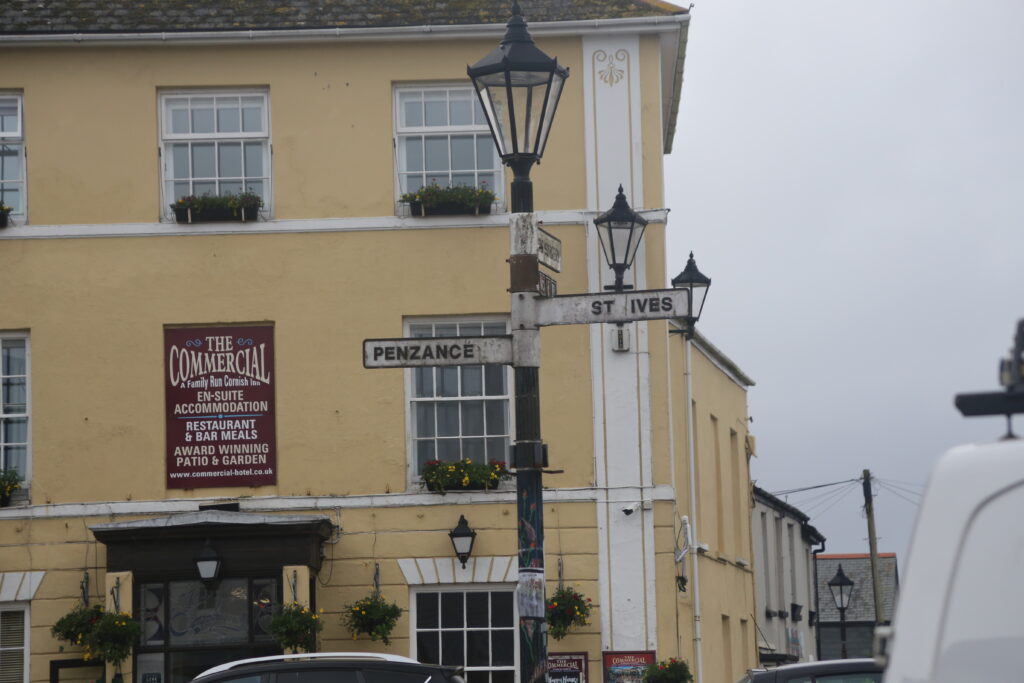 Street sign to Penzance and St Ives, with "The Commercial" restaurant behind