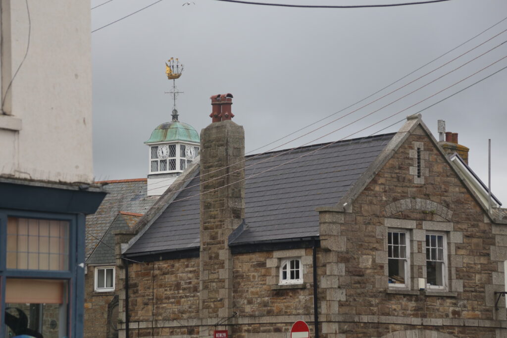 roof tops with copper verdigris clock tower and a weather vane in the shape of a sailing ship
